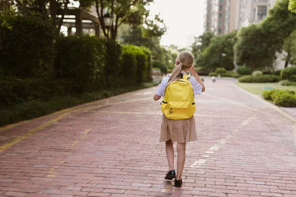 Zpátky do školy. Holčička se žlutým batohem ze základní školy venku. Dítě se bude učit nové věci 1. září za koncem Coronavirus covid-19 karantény a vlastní izolace — Stock fotografie