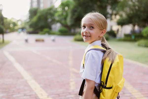 Zpátky do školy. Holčička se žlutým batohem ze základní školy venku. Dítě se bude učit nové věci 1. září za koncem Coronavirus covid-19 karantény a vlastní izolace — Stock fotografie