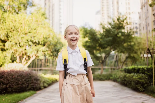 Uczennica wraca do szkoły po wakacjach. Uczeń w mundurze uśmiechnięty wczesnym rankiem na świeżym powietrzu. — Zdjęcie stockowe