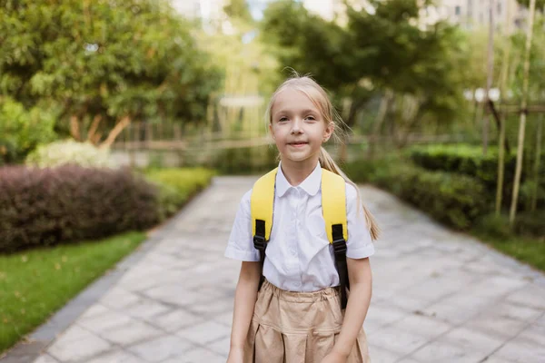 Η μαθήτρια επιστρέφει στο σχολείο μετά τις καλοκαιρινές διακοπές. Μαθητής με στολή χαμογελά νωρίς το πρωί εξωτερική. — Φωτογραφία Αρχείου