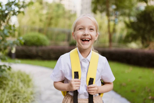 Školačka se po letních prázdninách vrací do školy. Žák v uniformě úsměv brzy ráno venku. — Stock fotografie