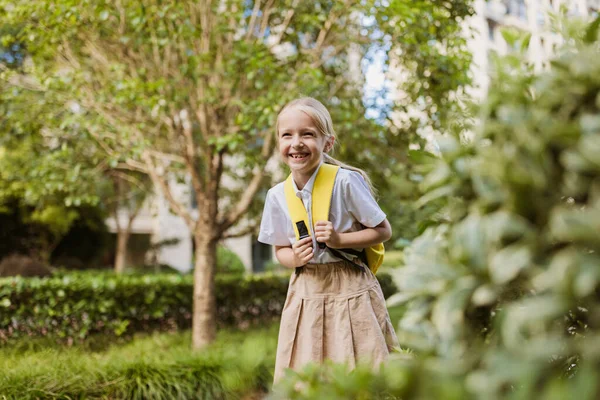 Schoolgirl back to school after summer vacations. Pupil in uniform smiling early morning outdoor. — Stock Photo, Image