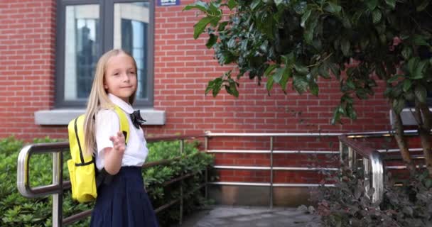 Felice piccola ragazza bionda caucasica di sette anni in uniforme con zaino giallo che torna a scuola dopo le vacanze estive o Coronavirus covid-19 quarantena. 4k rallentatore — Video Stock