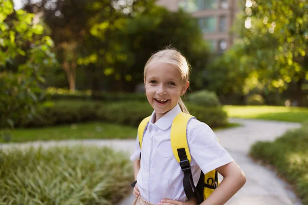 De vuelta a la escuela. Niña con mochila amarilla de la escuela primaria al aire libre. Kid going aprender cosas nuevas 1 de septiembre después de fin Coronavirus covid-19 cuarentena y autoaislamiento —  Fotos de Stock