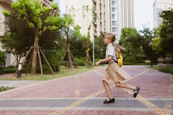 Školačka se po letních prázdninách vrací do školy. Dítě v uniformě úsměv brzy ráno venku. — Stock fotografie