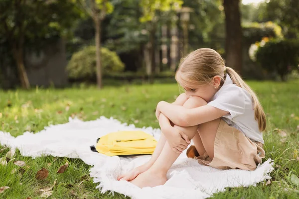 Okul çocuğu koronavirüs salgını sırasında parkta ya da arka bahçede çimenlerde tek başına oturuyor. — Stok fotoğraf