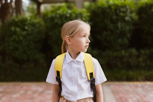 Colegiala de vuelta a la escuela después de las vacaciones de verano. Niño en uniforme sonriendo temprano en la mañana al aire libre. —  Fotos de Stock