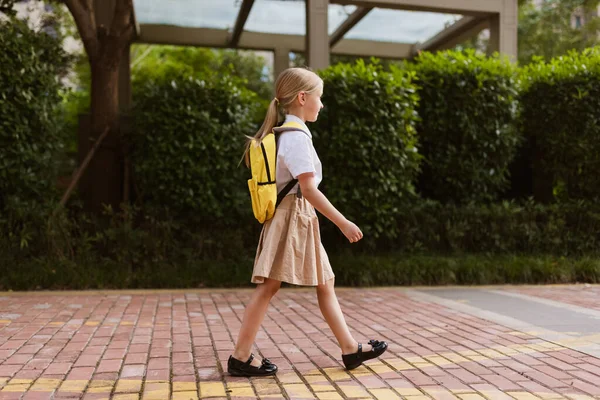 Écolière de retour à l'école après les vacances d'été. Enfant en uniforme souriant tôt le matin extérieur. — Photo