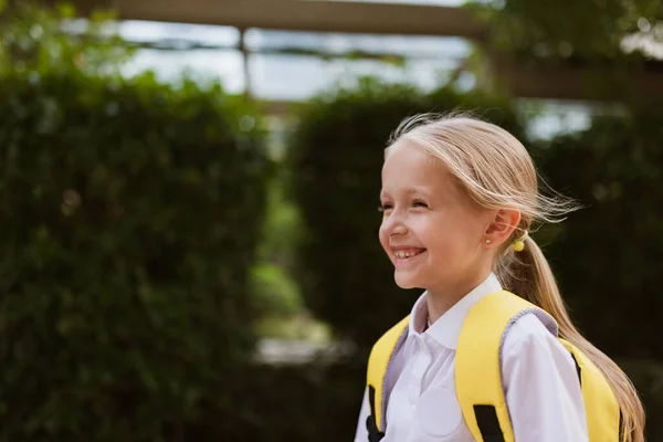 Skolflicka tillbaka till skolan efter sommarlovet. Barn i uniform ler tidigt på morgonen utomhus. — Stockfoto