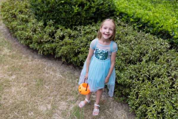 Menina loira em traje de princesa com abóbora lanterna no parque. Feliz conceito de Halloween — Fotografia de Stock