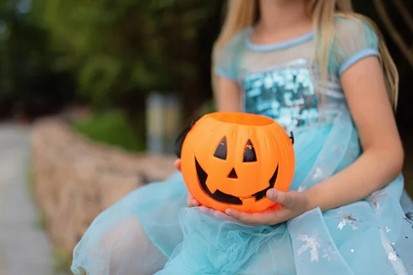 Lilla blonda flicka i prinsessdräkt med pumpa lykta i parken. Glad Halloween koncept — Stockfoto
