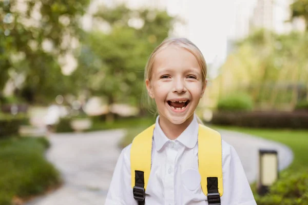 Schoolmeisje terug naar school na de zomervakantie. Pupil in uniform glimlachen vroeg in de ochtend buiten. — Stockfoto