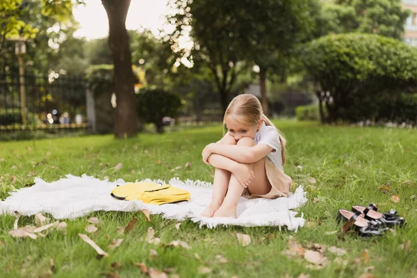 School child sitting alone on grass in park or backyard during coronavirus pandemic outbreak — Foto de Stock