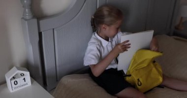 Beyaz tenli, üniformalı, sırt çantalı, evde sırt çantalı, Coronavirus covid-19 karantinasının sonundaki ilk gün için hazırlanan bir çocuk. Yavaş çekim