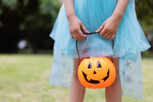 Lilla blonda flicka i prinsessdräkt med pumpa lykta i parken. Glad Halloween koncept — Stockfoto