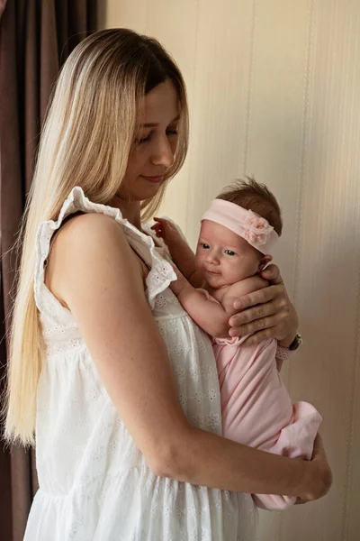 Portret van jonge blanke moeder houdt knuffel kleine pasgeboren baby twee weken oud thuis. gelukkig mam omarmt kleine zuigeling kind, shows liefde en zorg, kinderopvang concept — Stockfoto