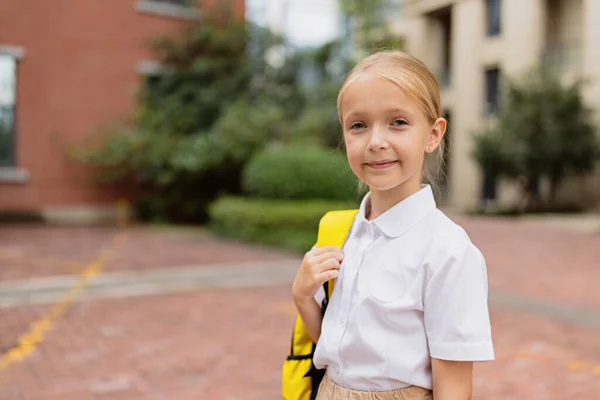 Studentessa torna a scuola dopo le vacanze estive. Bambino in uniforme in piedi la mattina presto all'aperto. — Foto Stock