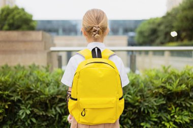 Yaz tatilinden sonra okula geri dönen kız öğrenci. Üniformalı çocuk sabahın köründe dışarıda duruyor.. 