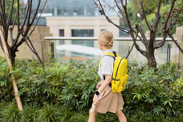 Školačka se po letních prázdninách vrací do školy. Dítě v uniformě stojící brzy ráno venku. — Stock fotografie