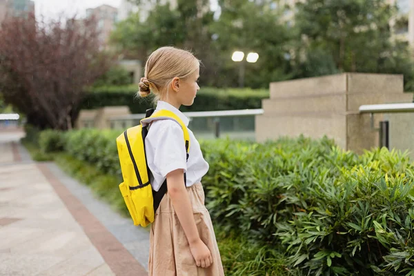 Η μαθήτρια επιστρέφει στο σχολείο μετά τις καλοκαιρινές διακοπές. Παιδί με στολή στέκεται νωρίς το πρωί εξωτερική. — Φωτογραφία Αρχείου