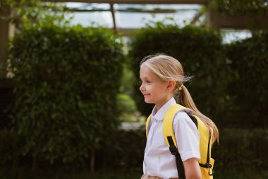Yaz tatilinden sonra okula geri dönen kız öğrenci. Üniformalı çocuk sabahın köründe dışarıda gülümsüyor.. 