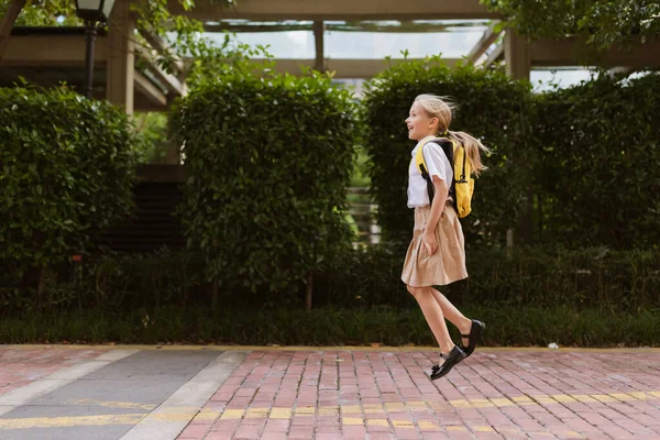 Školačka se po letních prázdninách vrací do školy. Dítě v uniformě úsměv brzy ráno venku. — Stock fotografie