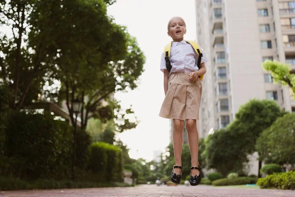 Yaz tatilinden sonra okula geri dönen kız öğrenci. Üniformalı çocuk sabahın köründe dışarıda gülümsüyor.. — Stok fotoğraf
