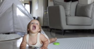 Otantik yakın plan. Beyaz bir kız bebek. Evdeki oturma odasında yerde oynuyor. Yavaş Hareket.
