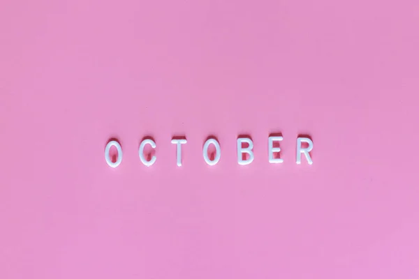 Flat lay vista superior da palavra outubro no fundo rosa. Outubro seu mês de conscientização do câncer de mama — Fotografia de Stock