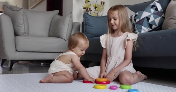 Dva roztomilí malí bělošští dětští sourozenci, kteří si doma hrají s dřevěnými hračkami. Koncept vývoje dětí. Malá holčička s blond vlasy hraje se starší sestrou. Zpomalený pohyb 4k — Stock video