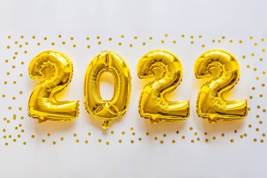 2022 yılınız kutlu olsun. Metalik balonlar beyaz üzerine altın rengi konfeti. Düz yatış, üst görünüm, model, genel giderler. Kış bayramı kutlaması