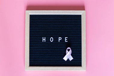 Göğüs kanseri farkındalığının simgesi olan pembe kurdeleli Umut kelimesinin düz bir görünümü vardı.