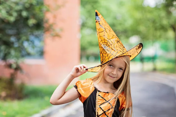 Portret życia Happy Little kaukaska dziewczyna z blond włosami siedem lat w czarnym pomarańczowym stroju, z których świętuje Halloween sam na świeżym powietrzu podczas Coronavirus covid-19 pandemia kwarantanny. — Zdjęcie stockowe