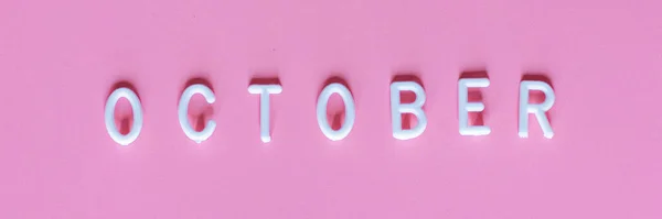 Piso laico vista superior de la palabra Octubre sobre fondo rosa. Octubre su mes de conciencia sobre el cáncer de mama —  Fotos de Stock