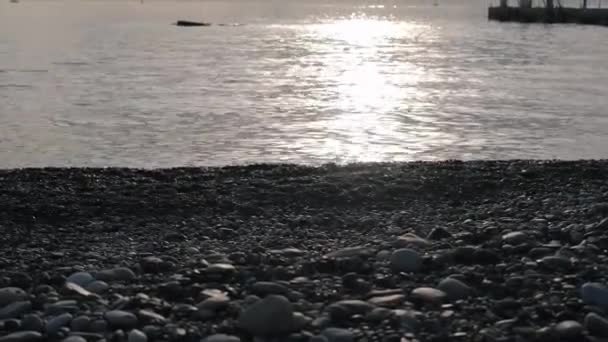 Pantai kerikil dekat laut melawan dermaga dengan menara penjaga yang aman — Stok Video