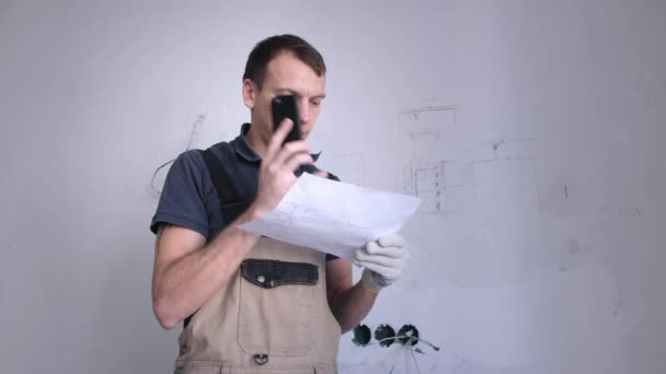 Handyman guarda il piano e consulta il proprietario dell'appartamento al telefono — Video Stock