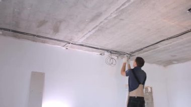 Kısa saçlı tamirci elektrik bağlantı kutuları kuruyor.