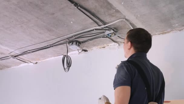 Handyman installeert elektrische doos op grijs betonnen plafond — Stockvideo