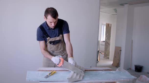 Man werknemer snijdt cornice gips fretwork met metalen zaag — Stockvideo