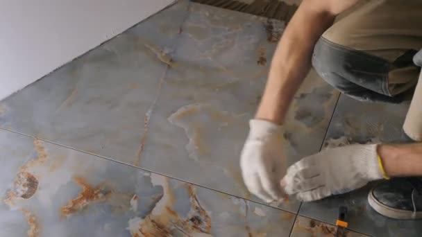 Майстер в рукавичках видаляє розчин з проміжків між плитками — стокове відео