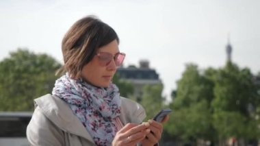 Pembe gözlüklü kadın internette telefonla dolaşıyor.