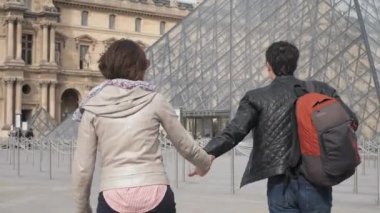 Yeni evli çift Louvre 'u ziyaret etmek için cam piramide yürür.