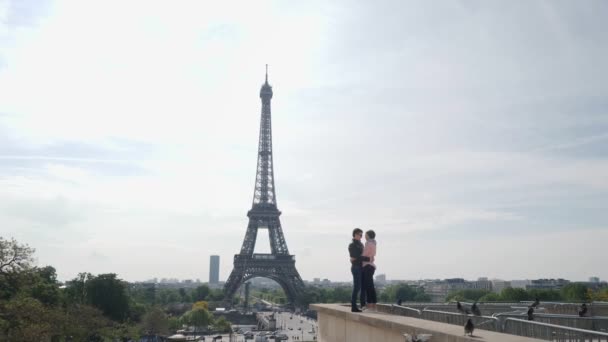 Nygifta par kyssar på parapet mot Eiffeltornet — Stockvideo