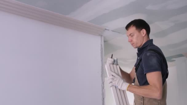 Handyman coloca moldagem de gesso no teto de concreto no quarto — Vídeo de Stock