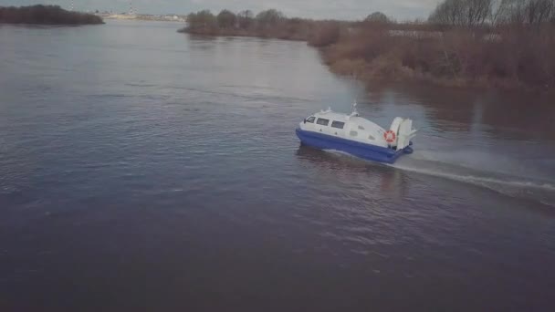 Blue white hovercraft with large propeller sails along river — Stock Video