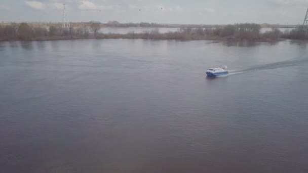 L'aéroglisseur bleu blanc navigue le long d'une large rivière après un bateau à moteur — Video