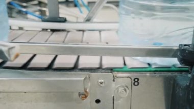 İçilebilir suyu olan şişeler dükkânda taşıyıcı bant boyunca hareket eder.