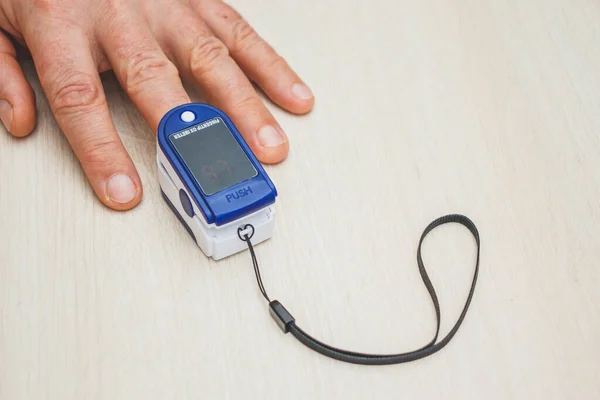 パルスと血中酸素濃度を測定するための小さなデジタルデバイス 指の上の酸素濃度計 コロナウイルスのパンデミックの現実 — ストック写真