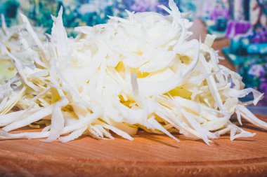 Pişirmek için dilimlenmiş sebze. Mutfak masasında duran yuvarlak ahşap bir tahtanın üzerindeki sebzeler. Kesilmiş lahana..