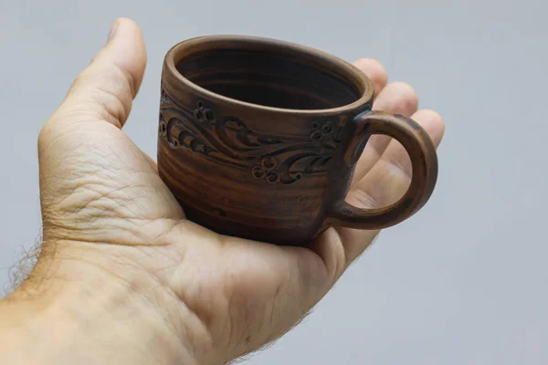 Barna kerámia csésze kezében egy könnyű háttér. — Stock Fotó